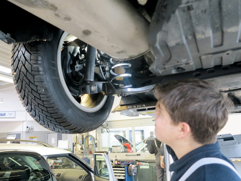 Mechaniker unterm Fahrzeug checkt die Reifengröße
